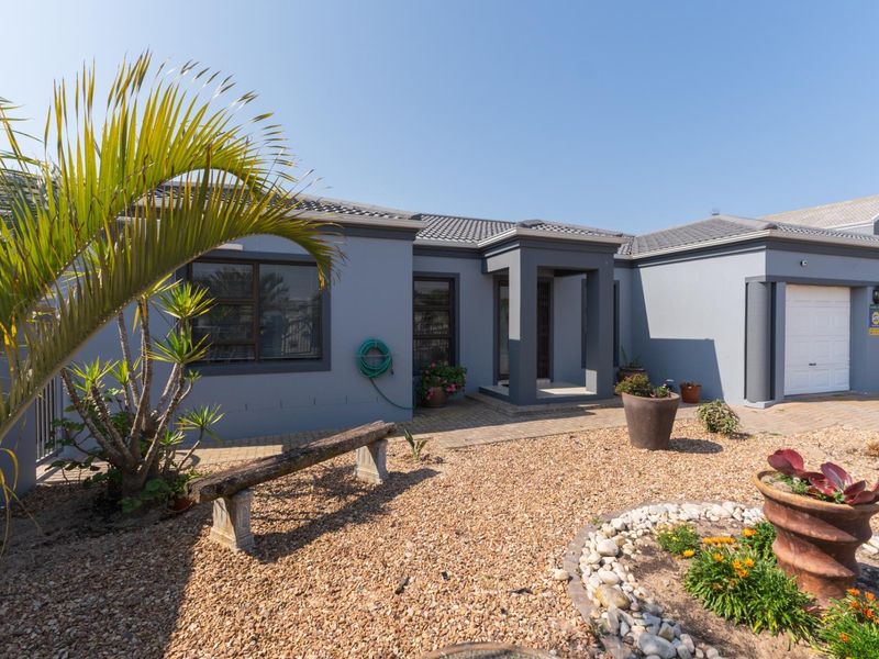 Front elevation of a modern single-story house featuring a tiled roof, double garage, and a paved entrance area with low-maintenance gravel landscaping.