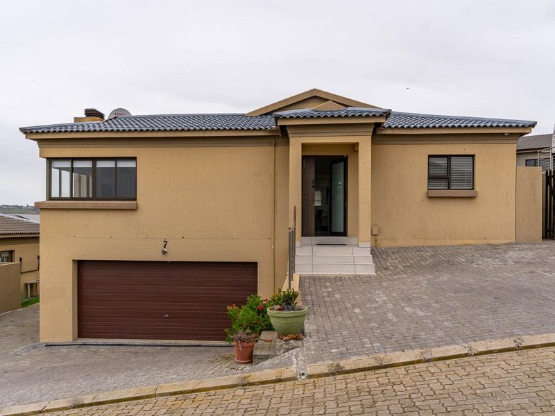 Front elevation of a modern house featuring a paved driveway, double garage, and tiled roof with neutral exterior wall finishes.