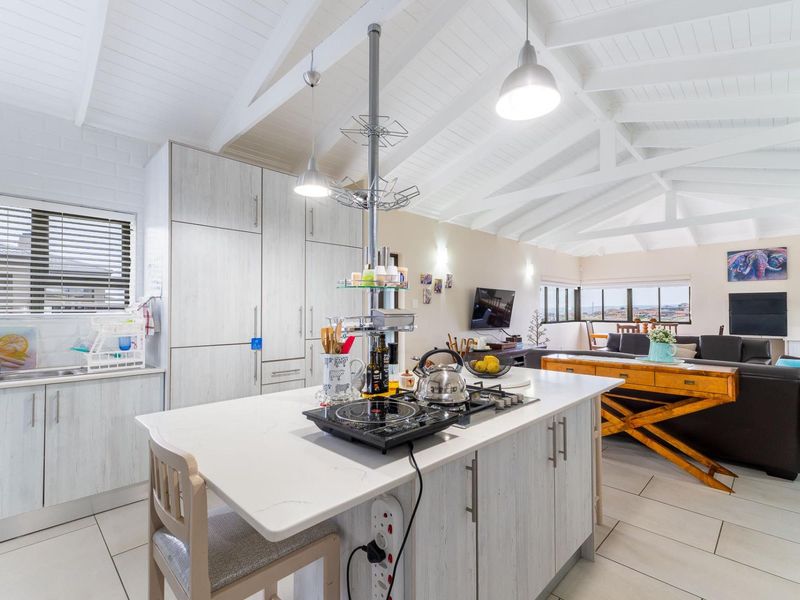 Spacious open-plan kitchen and living area featuring a central island, vaulted ceilings with exposed rafters, and modern cabinetry in a bright, airy layout.