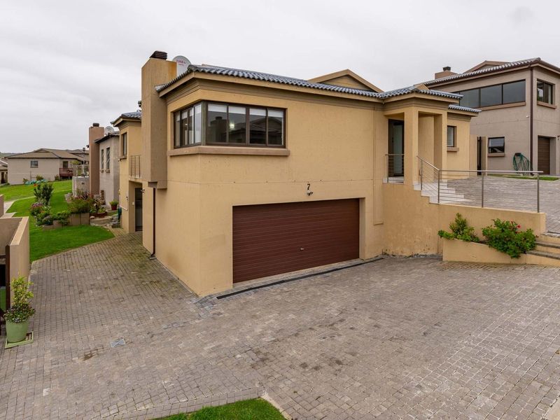 Front elevation of a multi-level residential property featuring a paved driveway, integrated double garage, and external staircase leading to the main entrance.