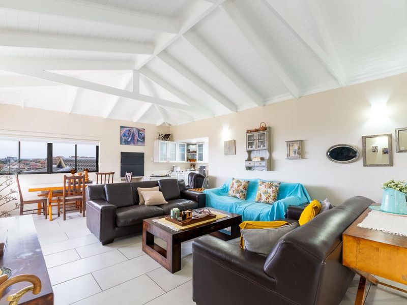 Spacious open-plan living and dining area featuring a high vaulted timber ceiling, tiled floors, and an integrated kitchen space.