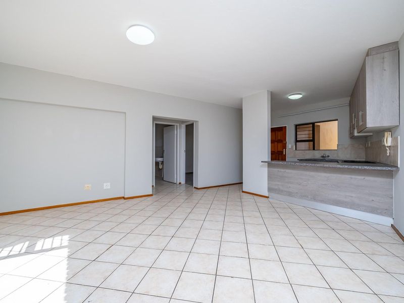 Spacious open-plan living area featuring tiled flooring and a functional kitchen with granite countertops and breakfast bar.