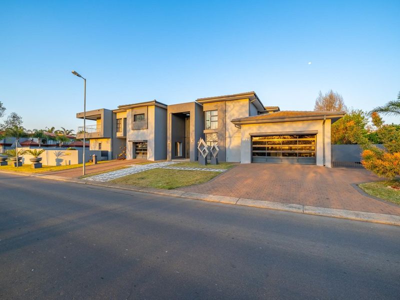 A modern double-story residential property featuring a paved driveway, double garage, and a contemporary architectural facade with a balcony.