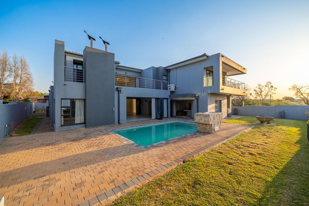 Modern double-story residence featuring a rear swimming pool, paved patio area, upper-level balconies, and well-maintained garden space.