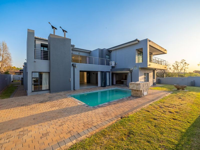 Modern double-story residence featuring a rear swimming pool, paved patio area, upper-level balconies, and well-maintained garden space.