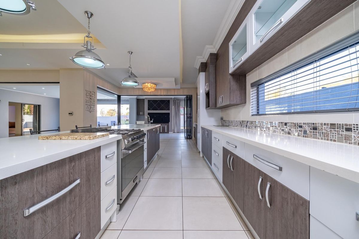 Modern kitchen featuring stone countertops, mosaic tile backsplash, high-end gas cooktop, built-in oven, and sleek two-tone cabinetry with ample storage space.