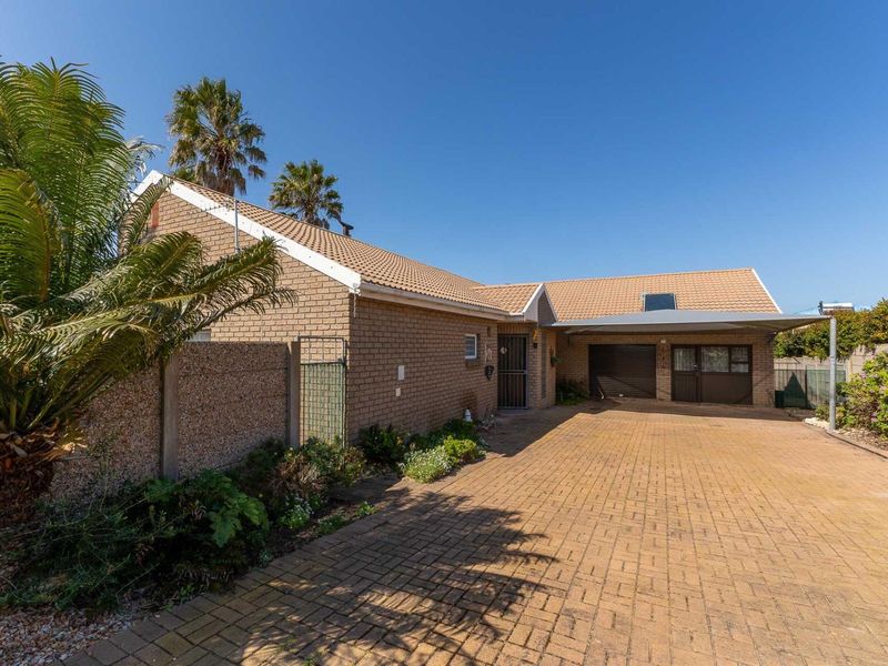 Front exterior view of a brick house featuring a paved driveway, carport, and secure garage access.