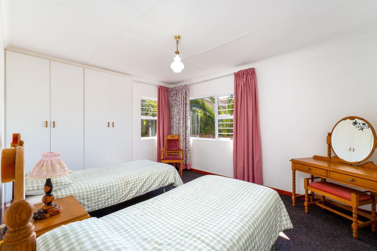 A functional bedroom featuring built-in cupboards, louver windows for ventilation, and carpeted flooring, offering a comfortable and practical living space.
