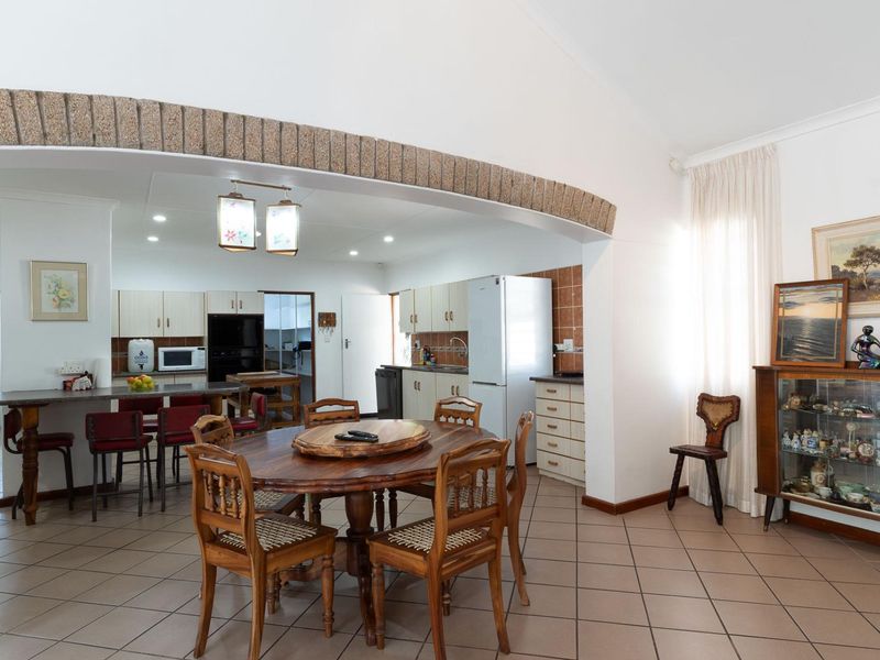 Open-plan kitchen and dining area featuring a distinctive stone-clad archway, tiled flooring, and functional built-in cabinetry with a breakfast bar.