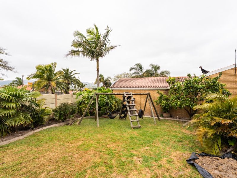A private rear garden featuring a lawn area, established palm trees, and perimeter boundary walls with electric fencing.