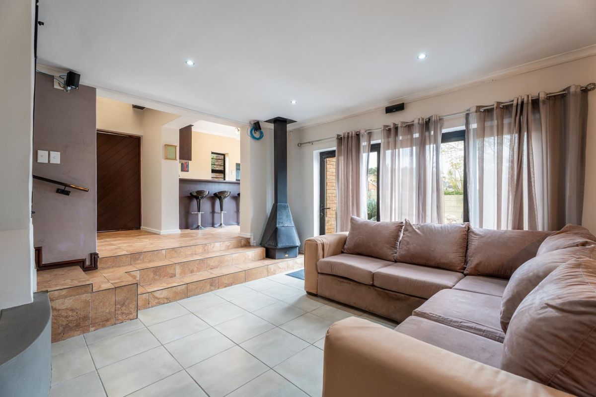 Spacious living room featuring a raised platform, tiled flooring, recessed lighting, and a prominent freestanding fireplace, with direct access to the outdoor area.