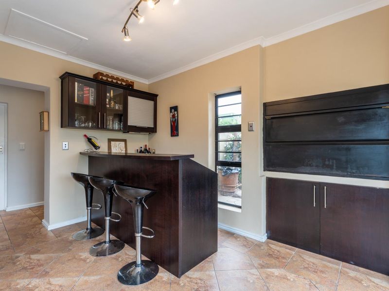 A dedicated bar area featuring a built-in counter, overhead cabinetry, and tiled flooring, providing a functional space for entertaining.