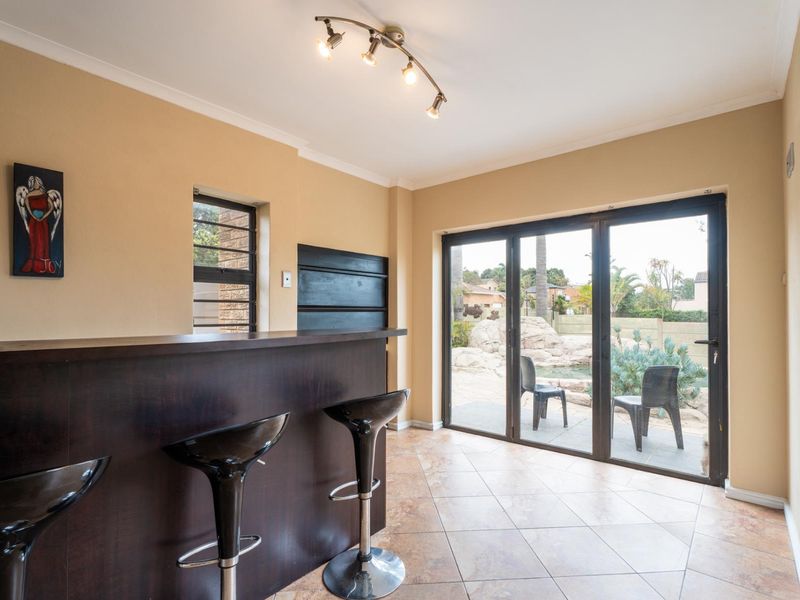 A well-lit bar area featuring a built-in counter, tiled flooring, and large sliding glass doors providing direct access to the outdoor patio and garden.