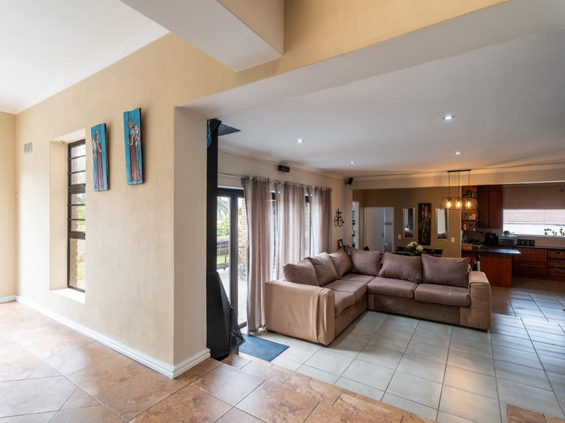 Spacious open-plan living area featuring tiled floors, recessed lighting, a built-in fireplace, and seamless flow into the kitchen space.