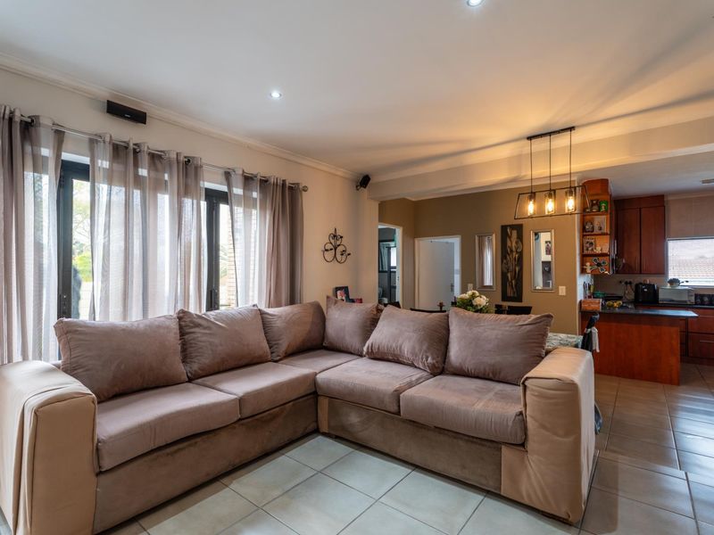 Open-plan living area featuring tiled floors, recessed lighting, and a connected kitchen with built-in cabinetry and island, leading to outdoor access via sliding doors.