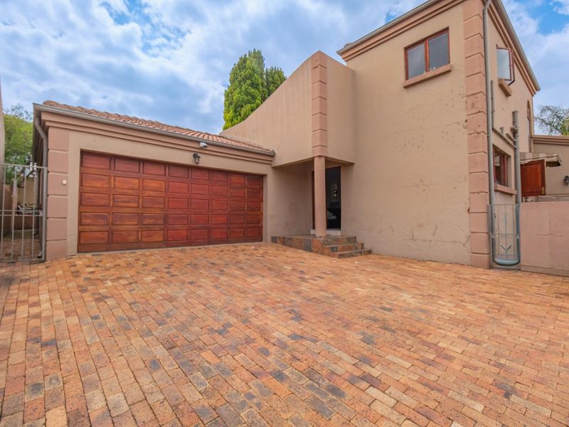 Front exterior view of a townhouse featuring a paved driveway, double garage, and stucco facade with a tiled roof.