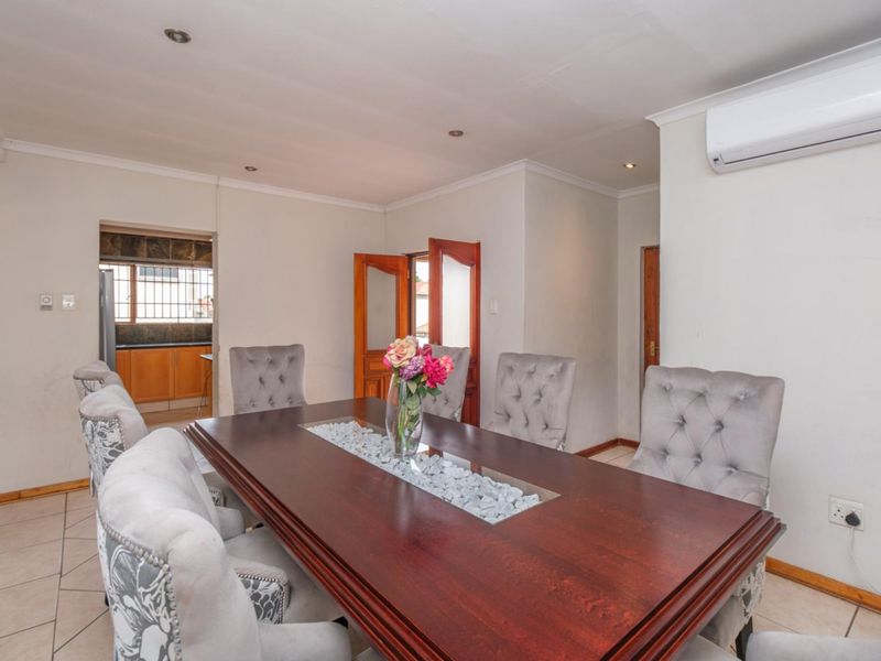 A dining room featuring tiled flooring, recessed downlighting, and a wall-mounted air conditioning unit, with an open transition to the adjacent kitchen area.