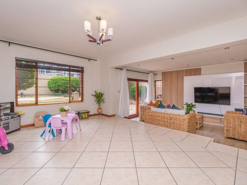 Spacious open-plan living area featuring tiled floors, a modern timber slat feature wall with built-in media unit, and direct access to the outdoor space.