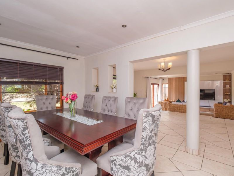 Open-plan dining and living area featuring tiled flooring, structural support column, and recessed wall niches, creating a spacious and connected layout.