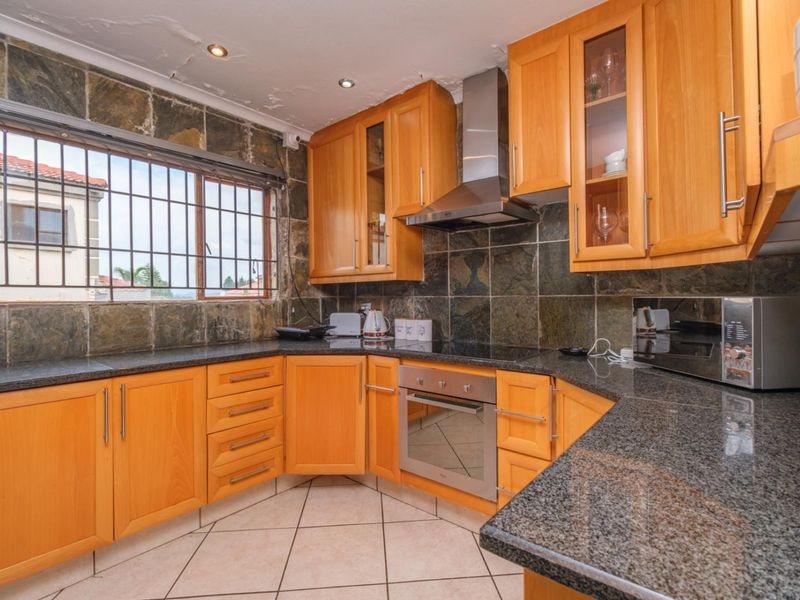 A functional kitchen featuring wooden cabinetry, granite countertops, built-in oven, and a stone tile backsplash. The ceiling requires maintenance and repair.
