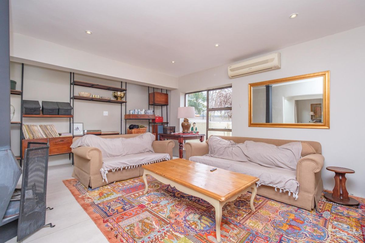 A comfortable living room featuring recessed downlights, a split-system air conditioner, and a built-in shelving unit, providing a functional and well-lit space.