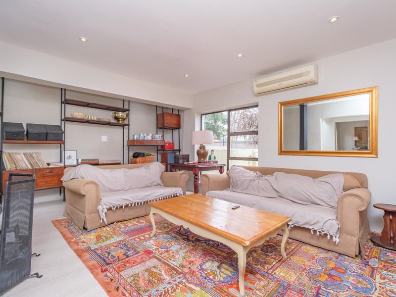 A comfortable living room featuring recessed downlights, a split-system air conditioner, and a built-in shelving unit, providing a functional and well-lit space.