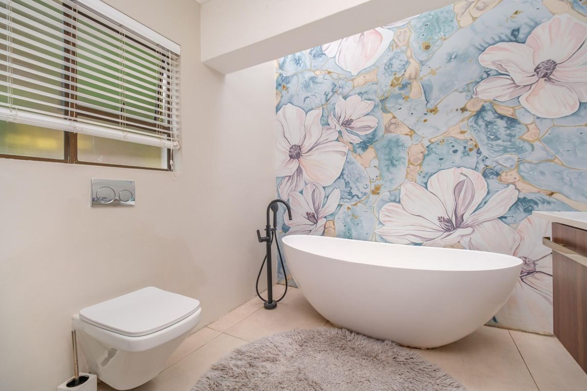 Modern bathroom featuring a sleek freestanding bathtub, wall-mounted toilet with concealed cistern, and a decorative floral feature wall.