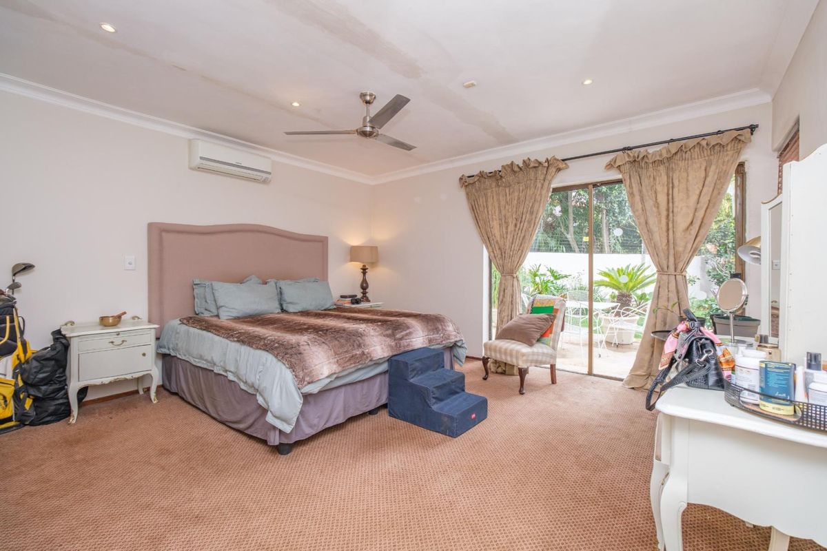 Spacious bedroom featuring carpet flooring, a ceiling fan, split-system air conditioning, and sliding glass doors providing direct access to the outdoor patio area.