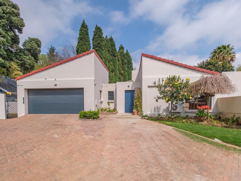 Front elevation of a residential property featuring a paved driveway, double garage, and a central entrance door with a tiled roof finish.