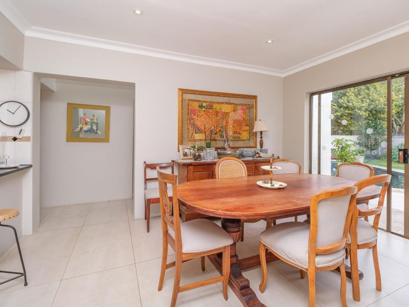 A bright dining room featuring tiled flooring, recessed lighting, and a large sliding glass door providing direct access to the outdoor pool area.