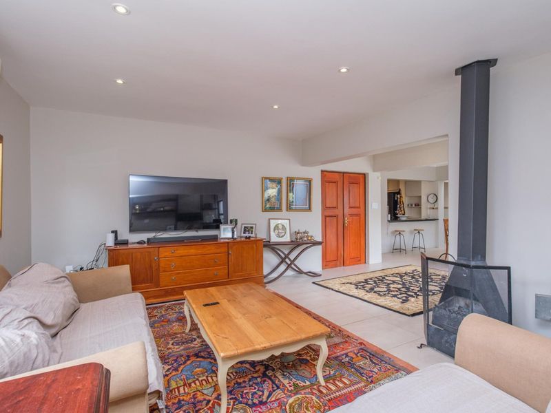 Spacious living room featuring a modern freestanding fireplace, tiled flooring, recessed lighting, and a split-system air conditioner, with an open flow to the kitchen area.