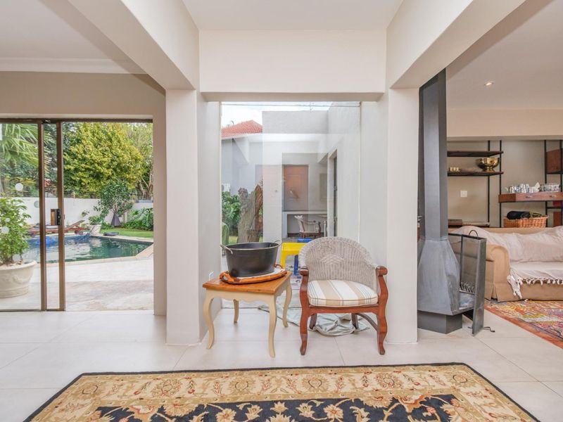 Spacious open-plan living area featuring tiled floors, a modern freestanding fireplace, and large sliding doors providing seamless access to the outdoor pool area.
