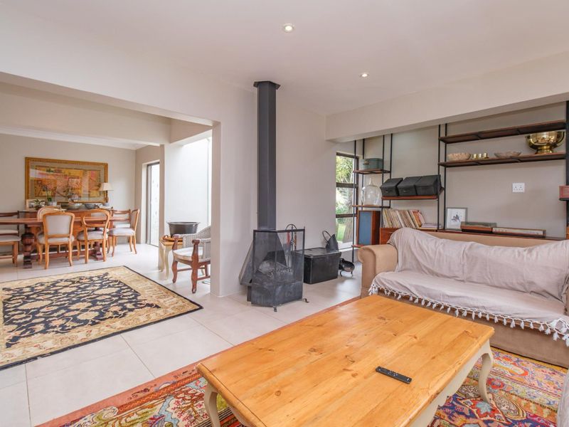 Spacious open-plan living and dining area featuring tiled floors, a central freestanding fireplace, and built-in shelving units.