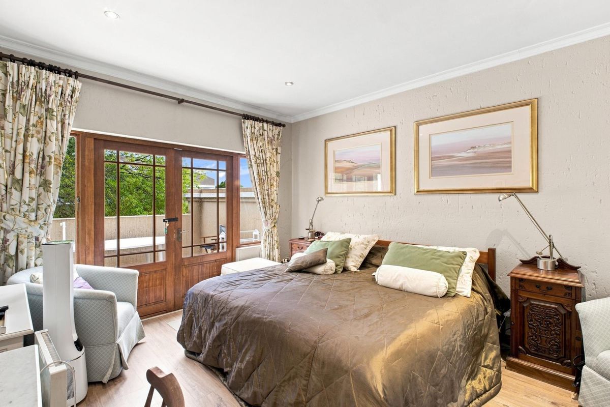 A well-maintained bedroom featuring laminate flooring, textured walls, and wooden French doors providing direct access to an outdoor area.