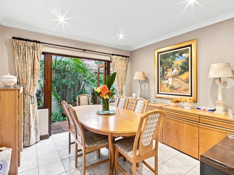 Dining room featuring tiled flooring, cornicing, and direct access to a private garden area through wooden doors.