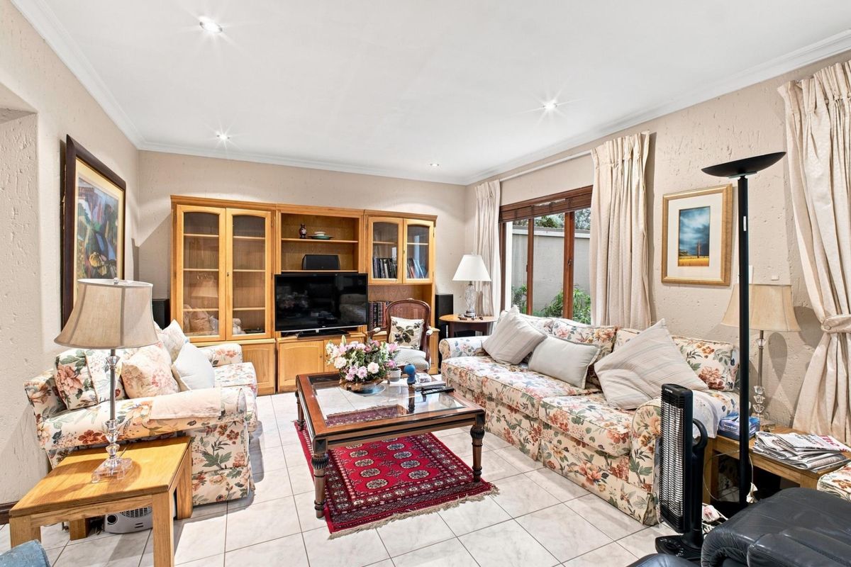 A comfortable living room featuring built-in wooden cabinetry, tiled flooring, and large sliding glass doors that provide natural light.