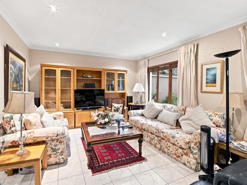 A comfortable living room featuring built-in wooden cabinetry, tiled flooring, and large sliding glass doors that provide natural light.