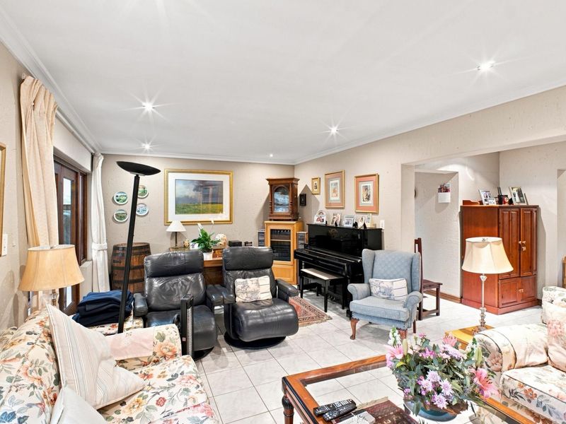 Spacious living room featuring neutral tiled flooring, recessed downlighting, and sliding glass doors providing access to the exterior.