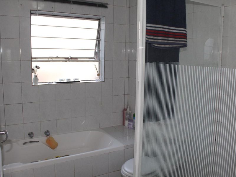 A functional bathroom featuring a built-in bathtub, a separate shower enclosure with a glass door, and tiled wall finishes.