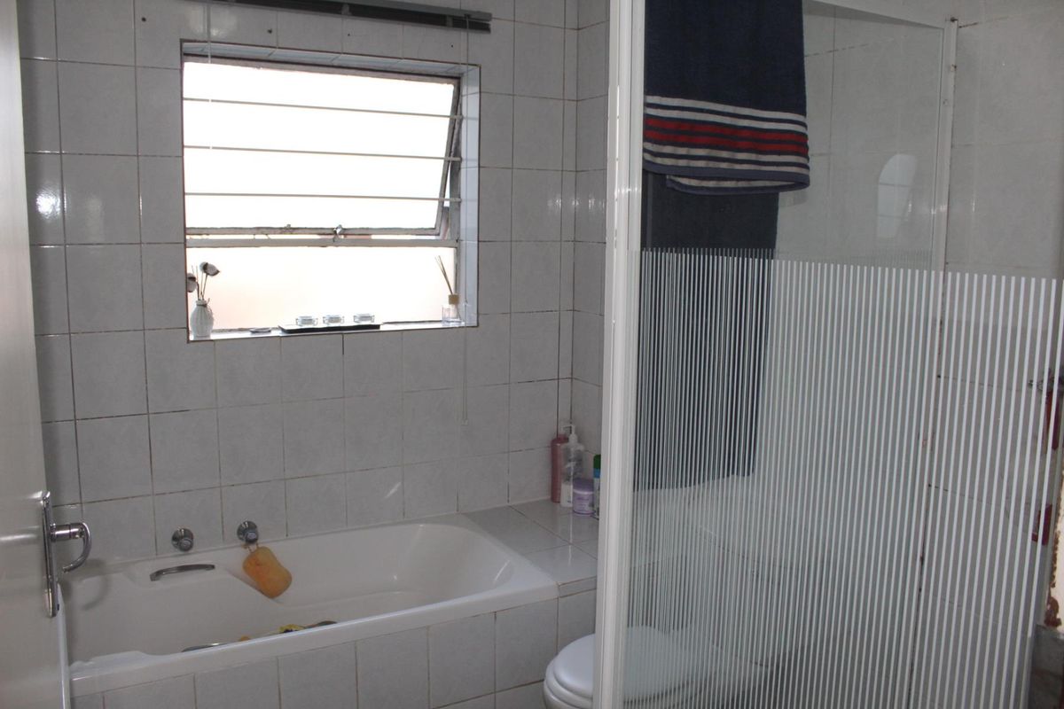 A functional bathroom featuring a built-in bathtub, a separate shower enclosure with a glass door, and tiled wall finishes.