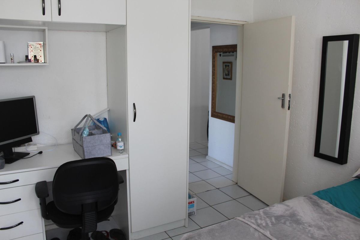 Bedroom featuring built-in cabinetry, a desk unit, and tiled flooring, with a doorway leading to an adjacent tiled hallway.