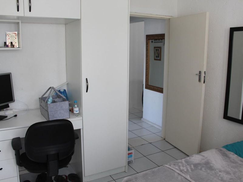 Bedroom featuring built-in cabinetry, a desk unit, and tiled flooring, with a doorway leading to an adjacent tiled hallway.