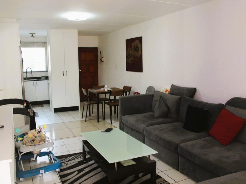 Open-plan living and kitchen area featuring tiled flooring, built-in cabinetry, and a functional layout suitable for modern apartment living.