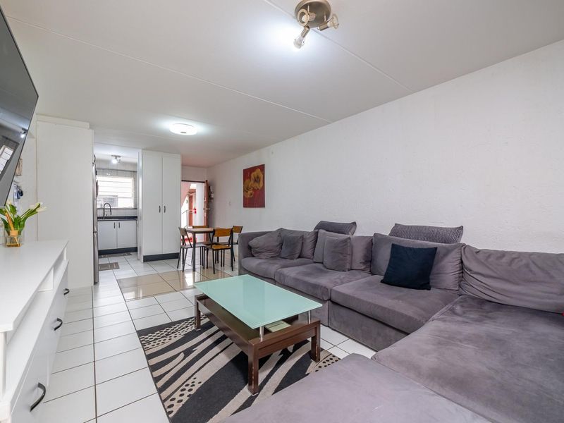 Open-plan living and dining area featuring tiled flooring and a functional kitchen space with built-in cabinetry.