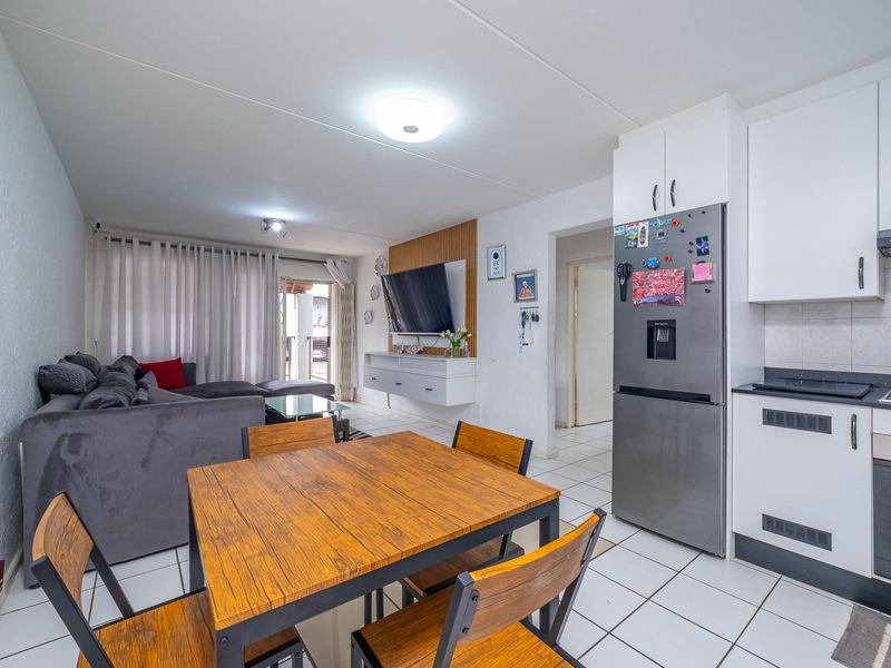 Open-plan living and kitchen area featuring tiled flooring, a modern slatted wood feature wall, and direct access to an outdoor patio space.