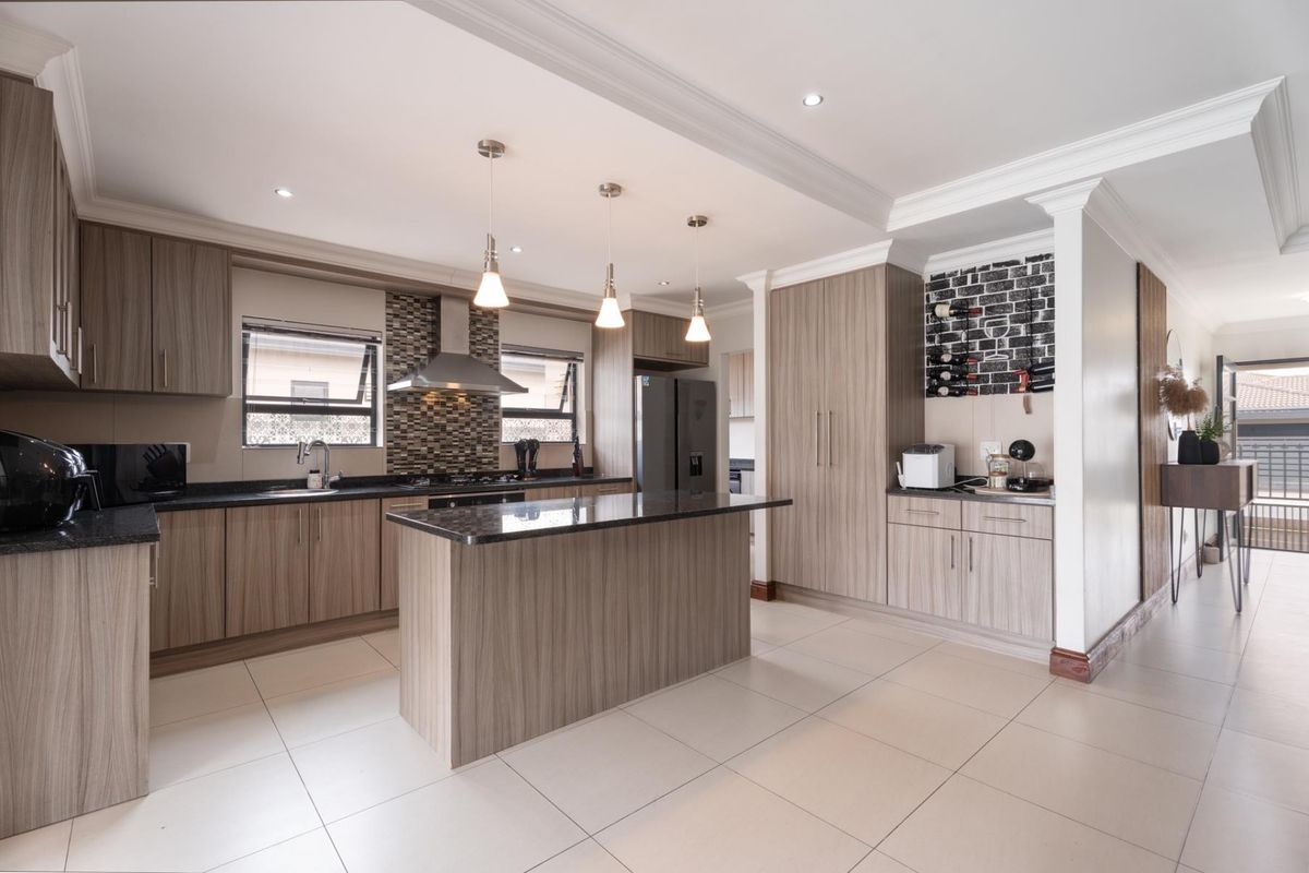Modern kitchen featuring wood-grain cabinetry, granite countertops, a central island, mosaic backsplash, and recessed lighting in an open-plan layout.
