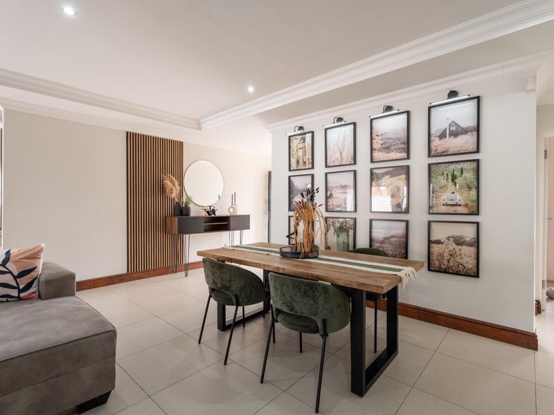 A well-appointed dining area featuring modern tiled flooring, decorative timber slat wall paneling, and elegant crown molding with recessed lighting.