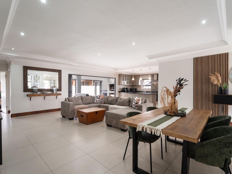 Spacious open-plan living and dining area featuring modern tiled floors, recessed lighting, and a stylish timber slat feature wall, seamlessly connecting to the kitchen.