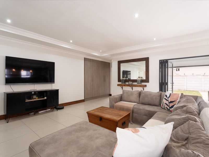 Spacious living room featuring tiled flooring, recessed ceiling lighting, built-in storage cabinetry, and bi-fold doors providing seamless access to the outdoor area.