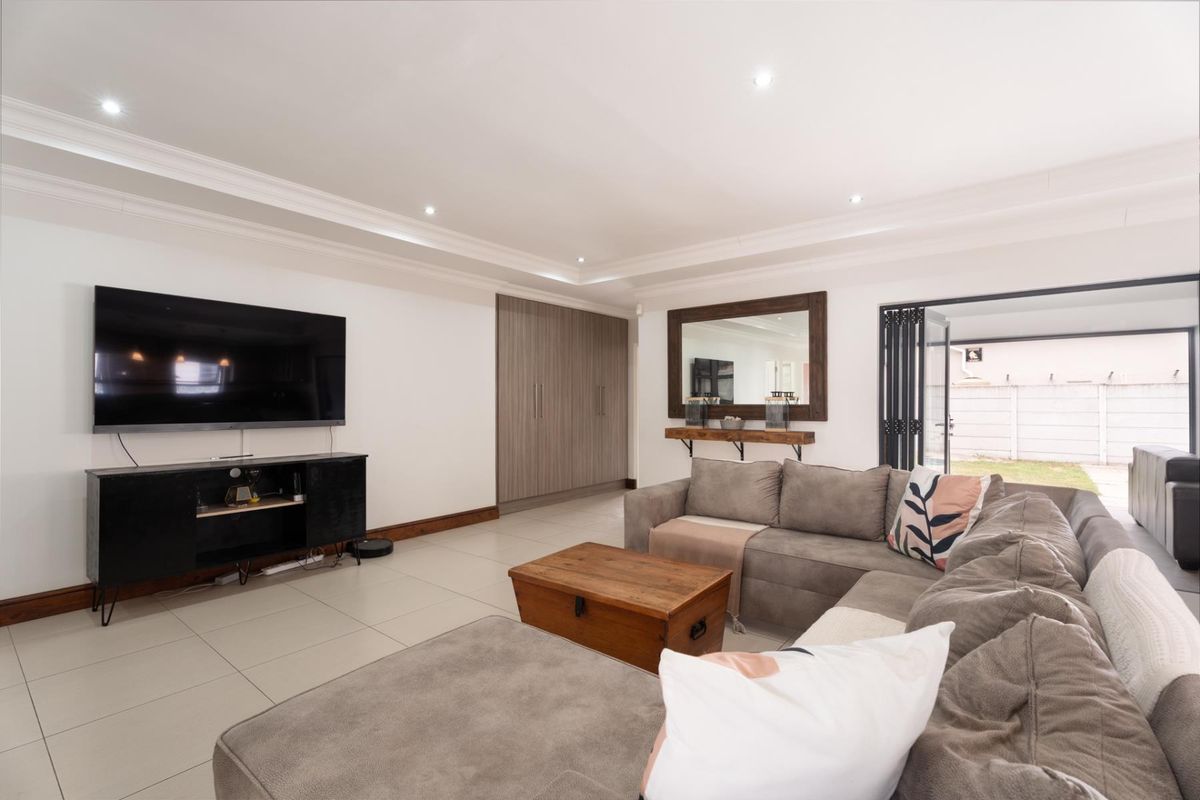 Spacious living room featuring tiled flooring, recessed ceiling lighting, built-in storage cabinetry, and bi-fold doors providing seamless access to the outdoor area.